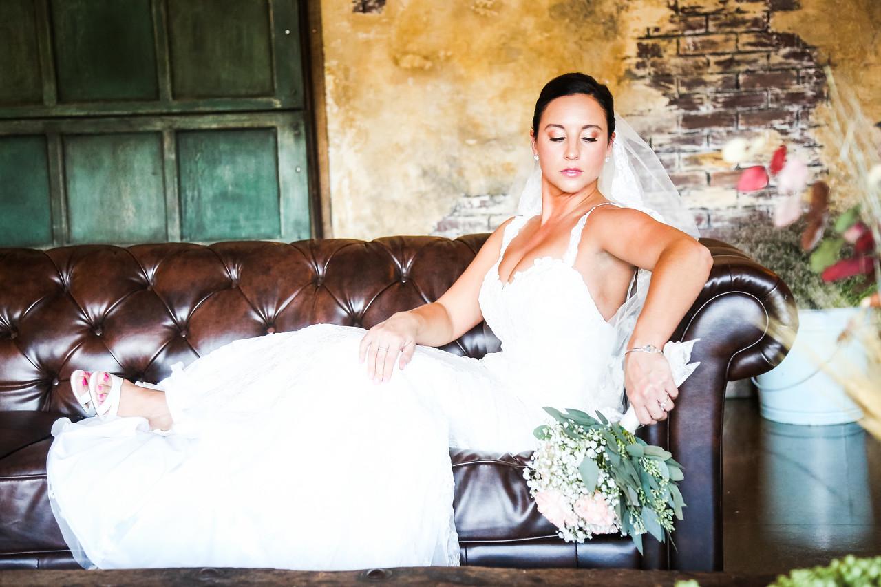 A bride sitting on leather sofa with gorgeous airbrushed makeup